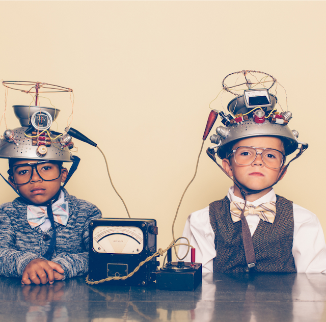 Two young kids looking miserable in a fake science experiment with hats on their heads