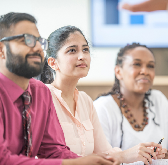 Three people in audience listening to a talk