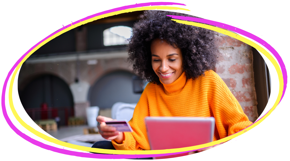 A black woman smiling a lot with her iPad and credit card shopping online