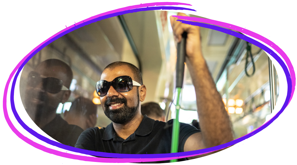 A black blind man sitting on a bus smiling and holding a cane